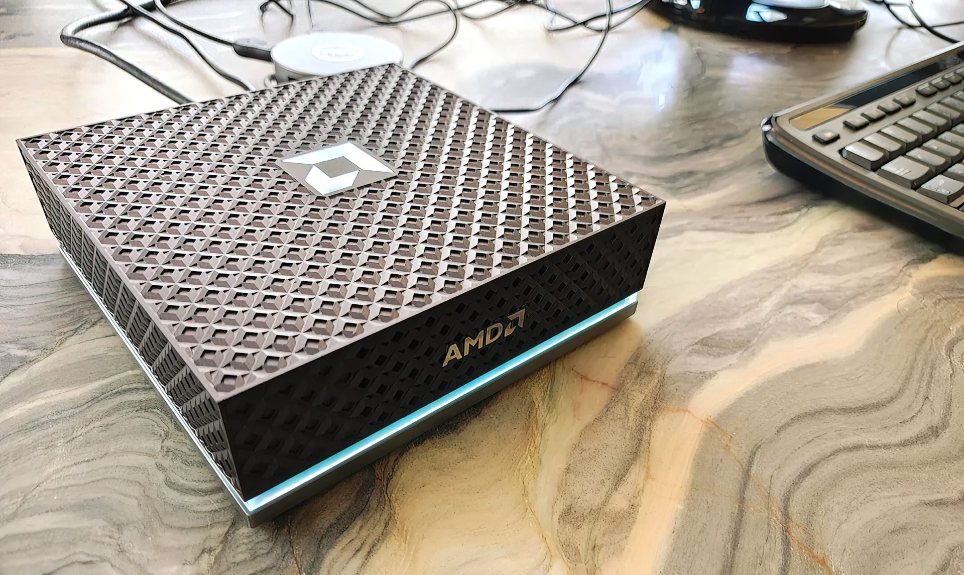 A compact black mini PC with a subtle LED accent light, labeled as AMD Ryzen AI Halo.