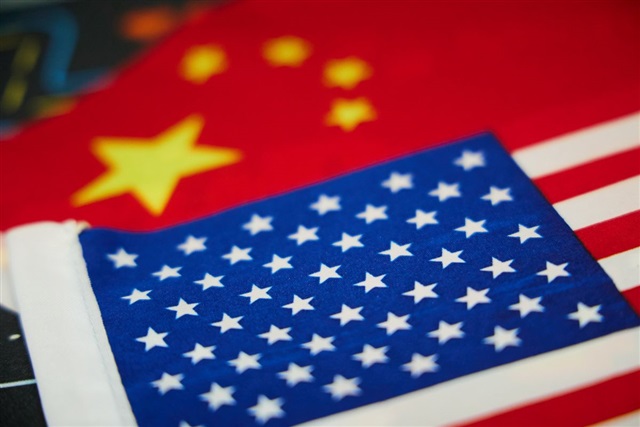 A handshake between two figures, representing US and China leaders, with a backdrop of circuit board patterns and financial charts.
