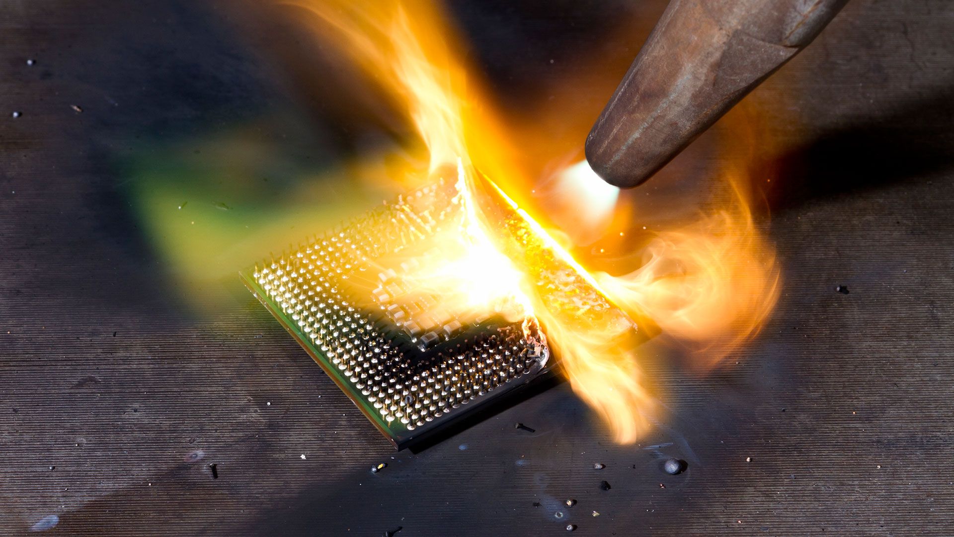 Close-up of a CPU die with etched patterns, slightly scorched around the edges, illuminated under a microscope.