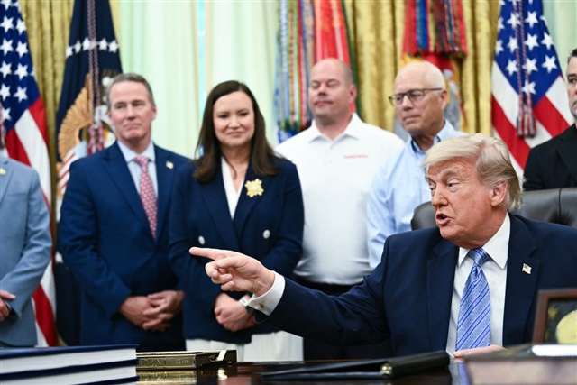 President Donald Trump speaking at a podium in the Oval Office.