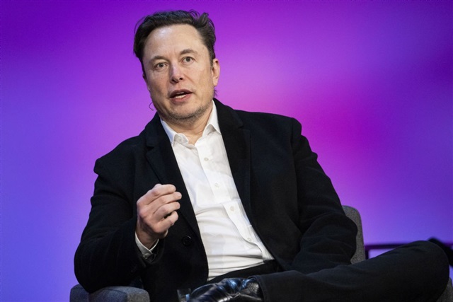 Elon Musk looking thoughtfully at a server rack with glowing lights.