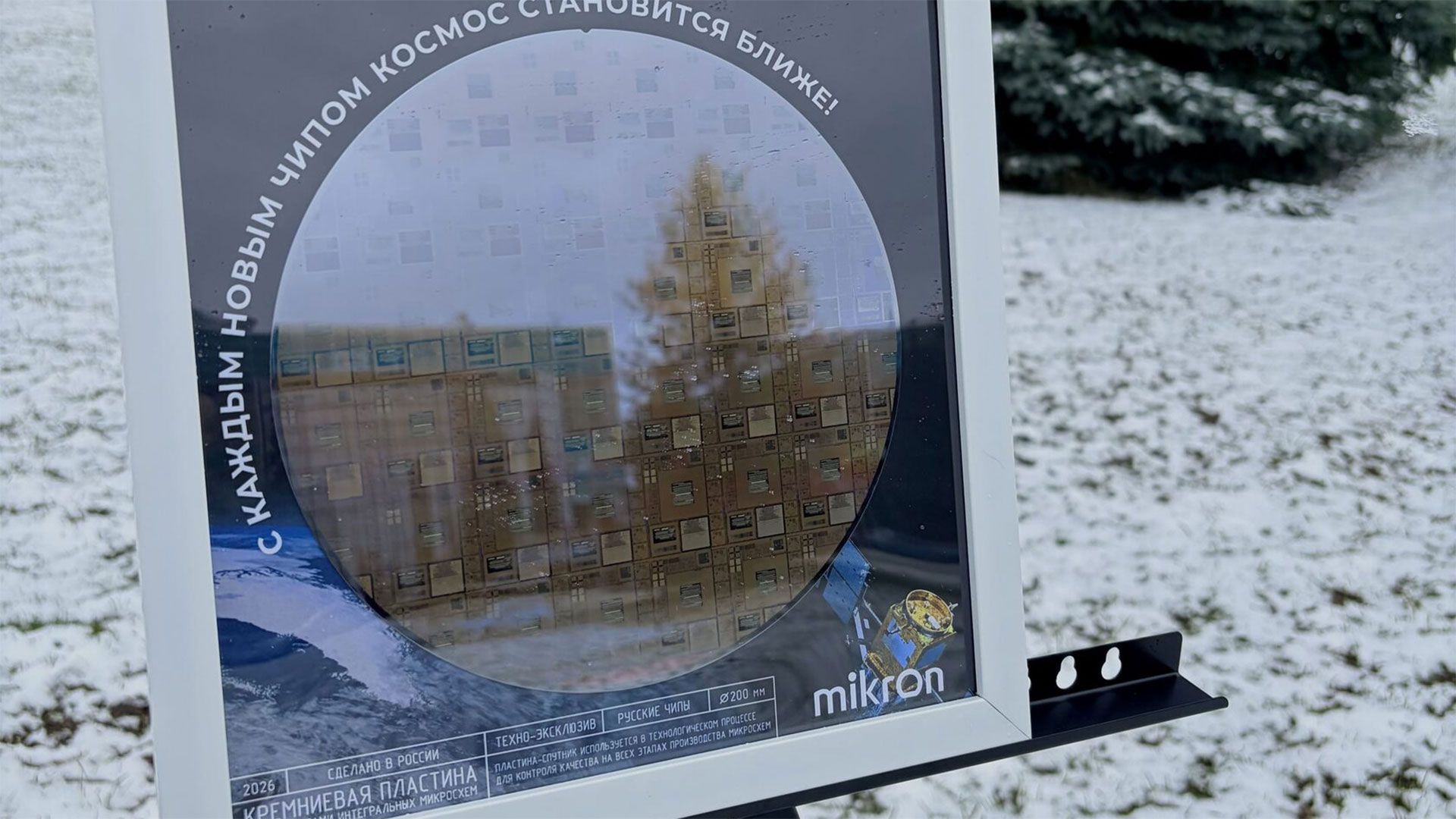 A framed silicon wafer with microchips visible, displayed on a wall.