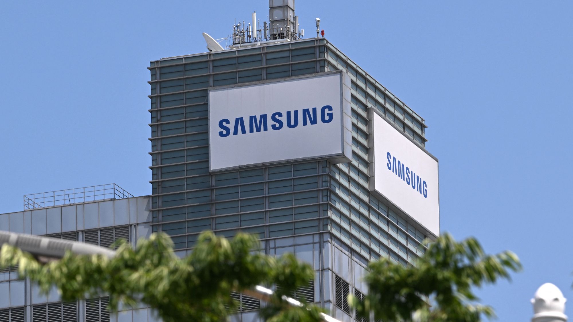A split image showing a Samsung semiconductor chip on one side and a group of unhappy-looking Samsung employees on the other.