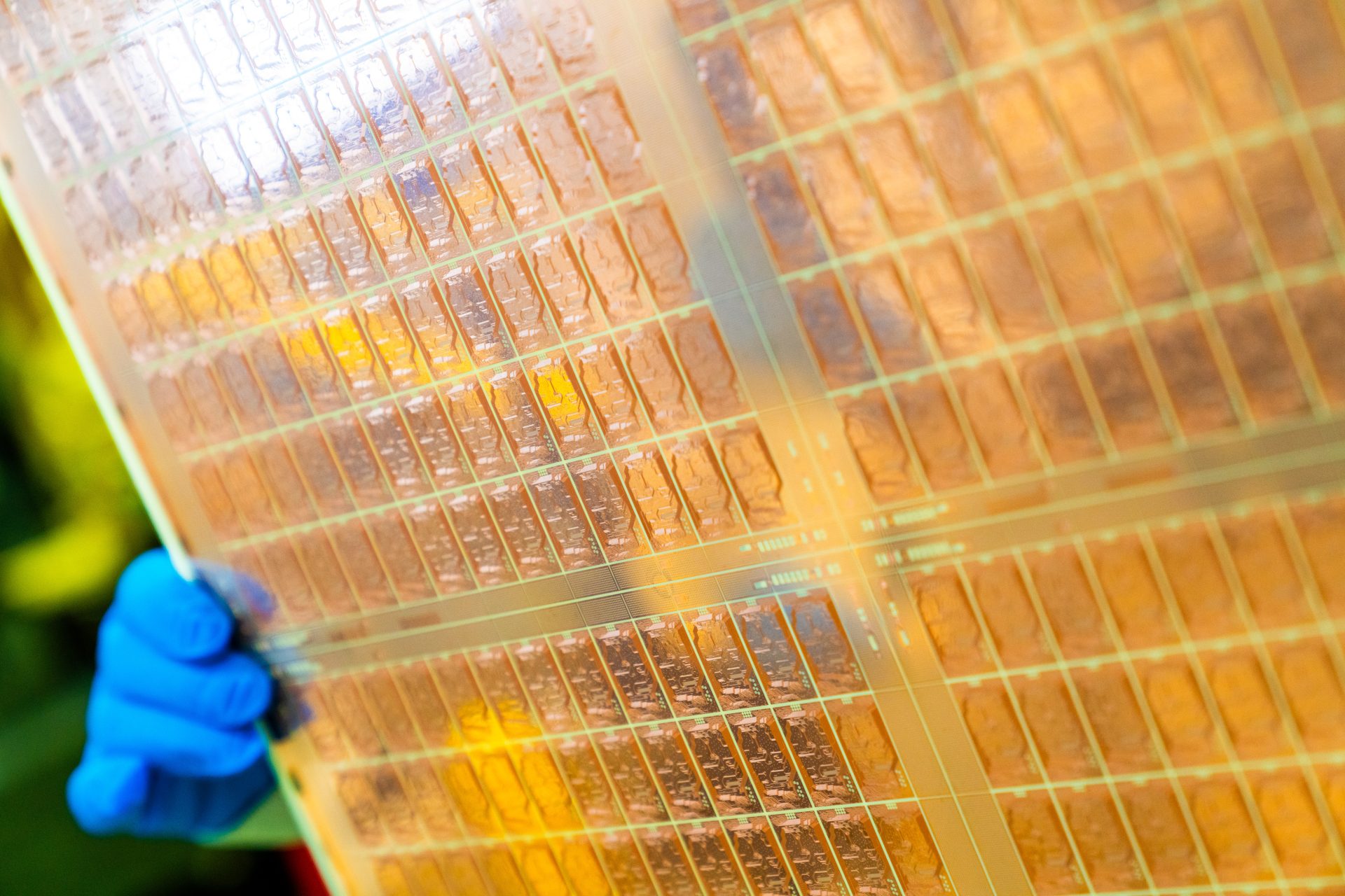 Prototype of Intel's Glass Core Substrate showing multiple chiplets and yellow co-packaged optical modules on a transparent glass wafer.